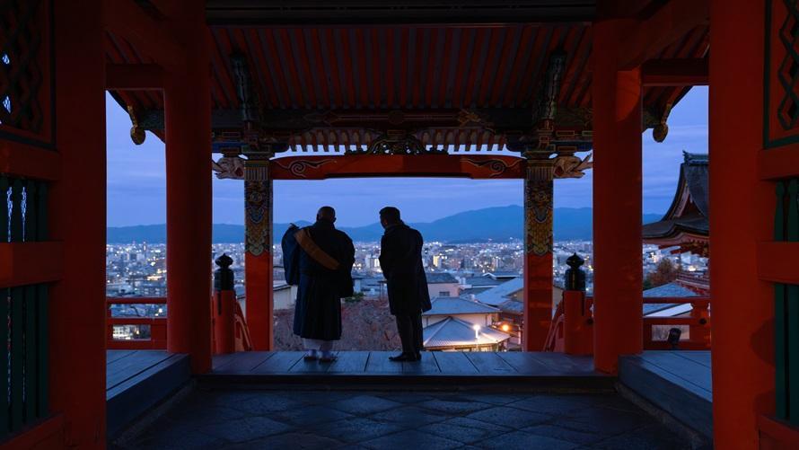 早朝の清水寺で僧侶の案内のもと通常非公開の場所から街を眺める男性